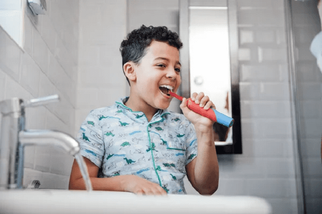 little boy brushing his teeth with an electric toothbrush
