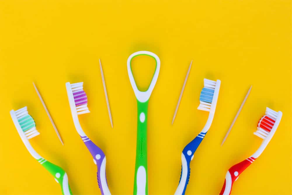 tongue scraper surrounded by toothbrushes